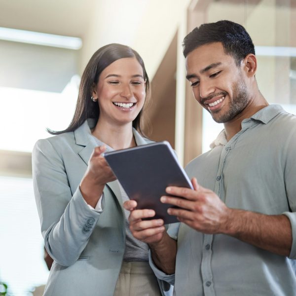 im-so-glad-i-found-you-shot-of-two-coworkers-talking-while-using-a-digital-tablet-